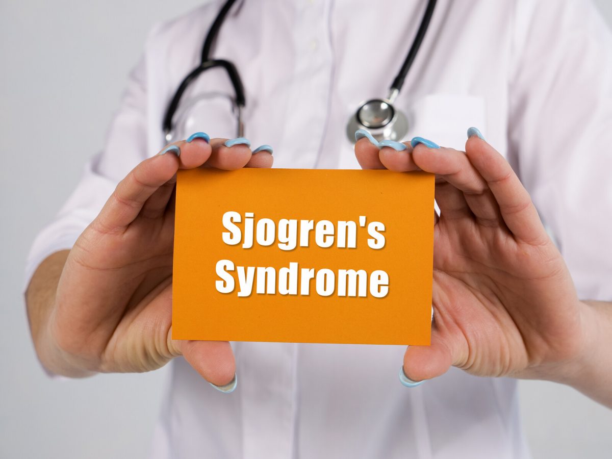 Healthcare professional holding sign that says 'Sjogren's Syndrome.'