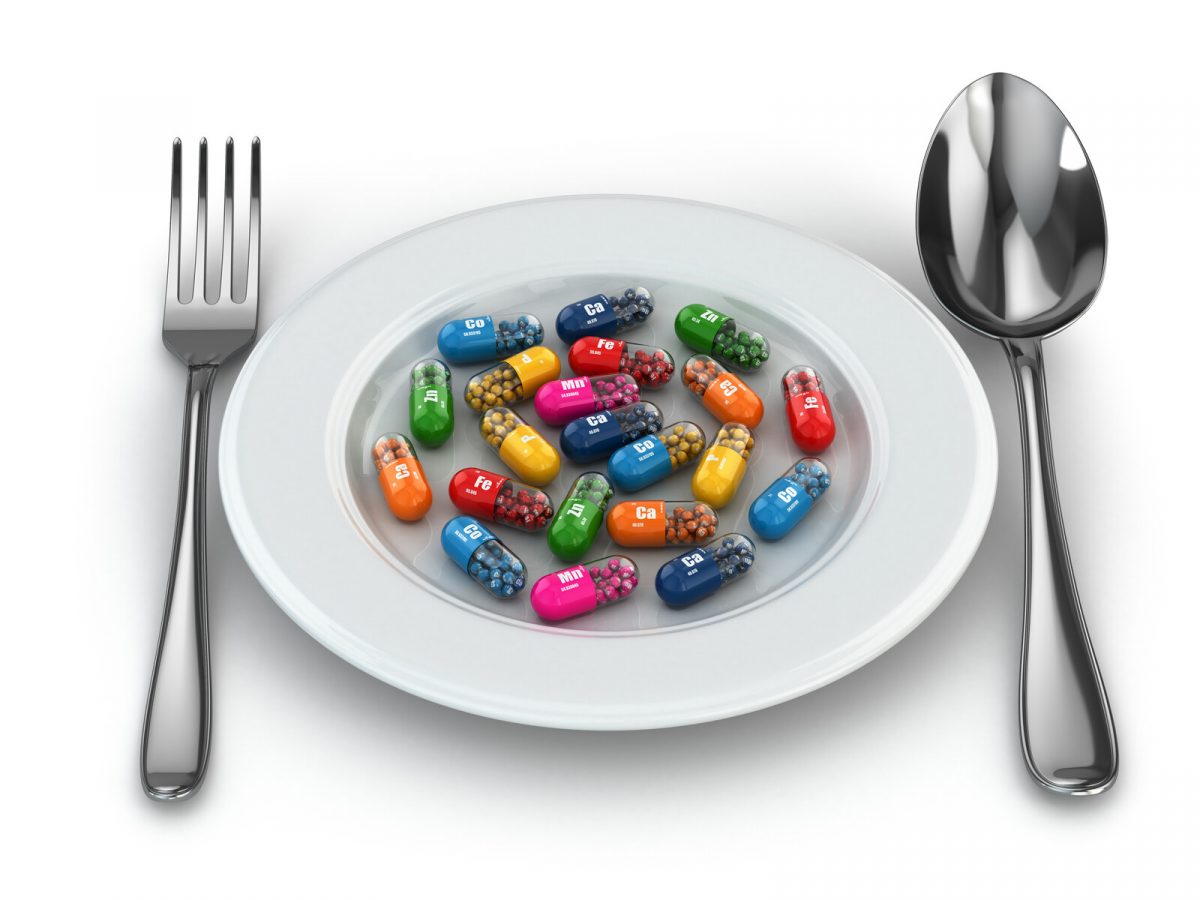 Image of a dinner plate filled with various colored medication capsules.